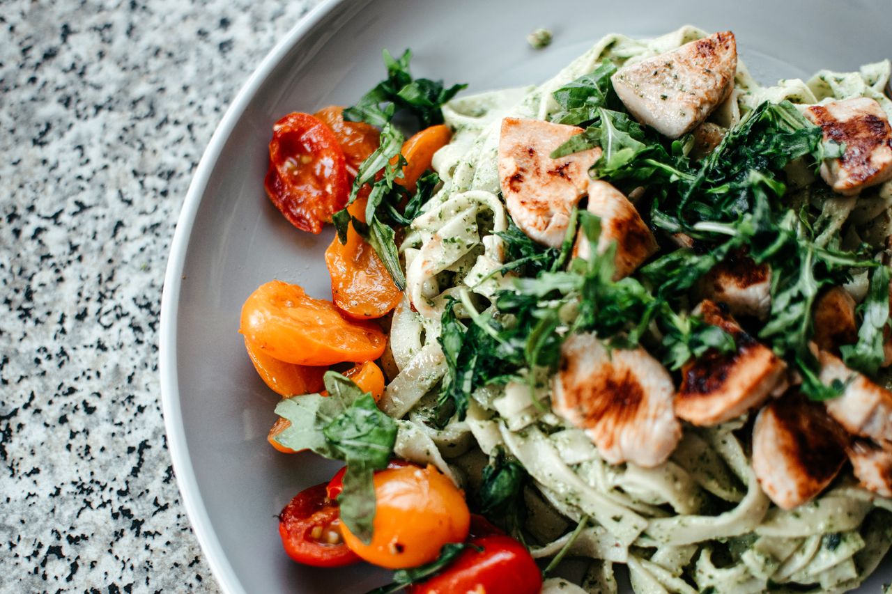 Savor a plate of chicken pesto pasta topped with fresh herbs and juicy cherry tomatoes.